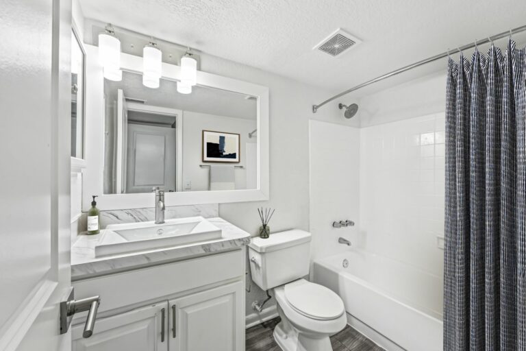 Bright and modern bathroom with elegant marble countertop, sleek fixtures, and stylish lighting, creating a luxurious spa-like atmosphere.